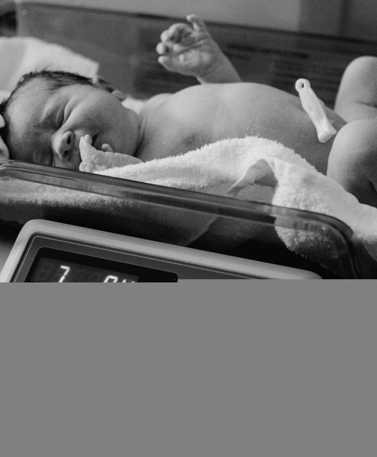 a black and white photo of a baby in a hospital bed with a thermometer