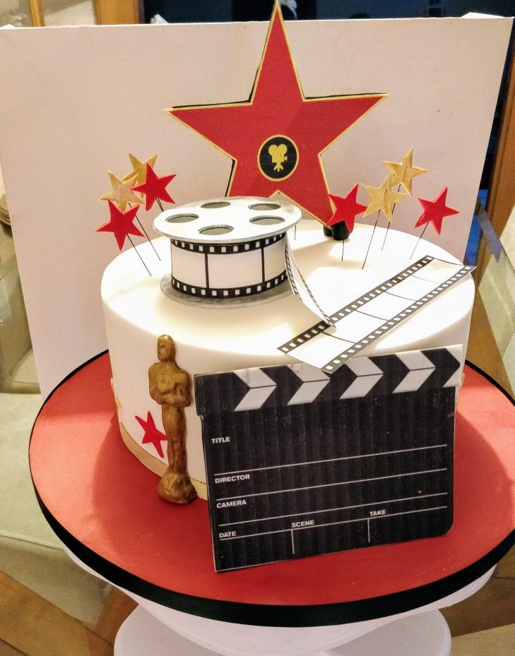 a cake with a movie clapper and star on the top is sitting on a table