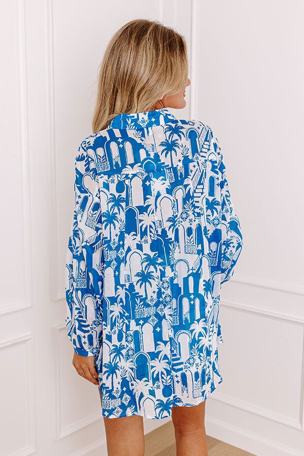 - Add a touch of the tropics to your wardrobe with this chic button-up! With its lightweight material and tropical-themed print, this piece is perfect for a walk down a breezy boardwalk. Whether you're heading to a beachside cafe or enjoying a sunset cruise, this shirt brings a vacay vibe to any occasion. - Unlined semi-sheer lightweight material with an abstract tropical cityscape print - A collared neckline - A button up front - Long sleeves with button closure cuffs - Functional chest pockets Blue Hawaiian Shirt For Summer, Palm Tree Print Button-up Beach Tops, Blue Hawaiian Shirt With Button Closure For Summer, Beach Hawaiian Shirt With Button Closure, Hawaiian Shirt With Button Closure For Beach, Spring Vacation Hawaiian Shirt With Button Closure, Beach Tropical Print Button-up Top, Tropical Print Button-up Top For Beach, Tropical Print Button-up Beach Top