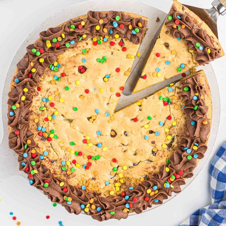 a cake with chocolate frosting and sprinkles on it, being cut by a knife