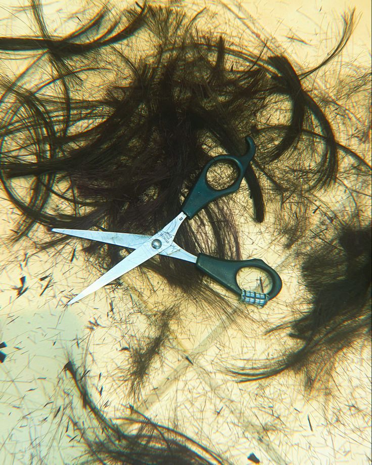 a pair of scissors sitting on top of a pile of hair