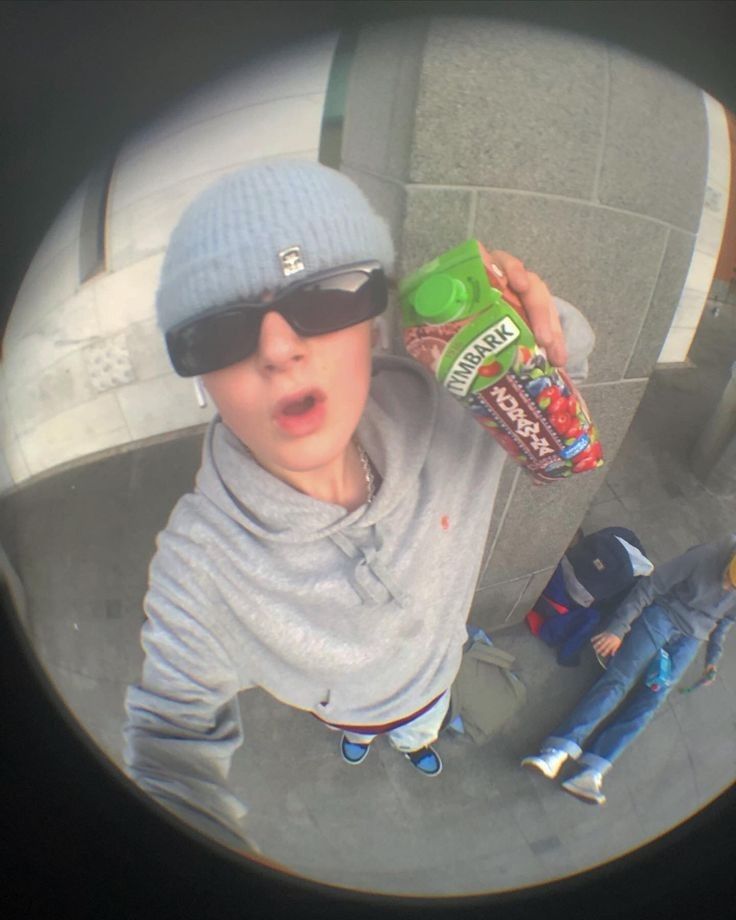 a young boy wearing sunglasses and a hat holding a bag of chips in front of him