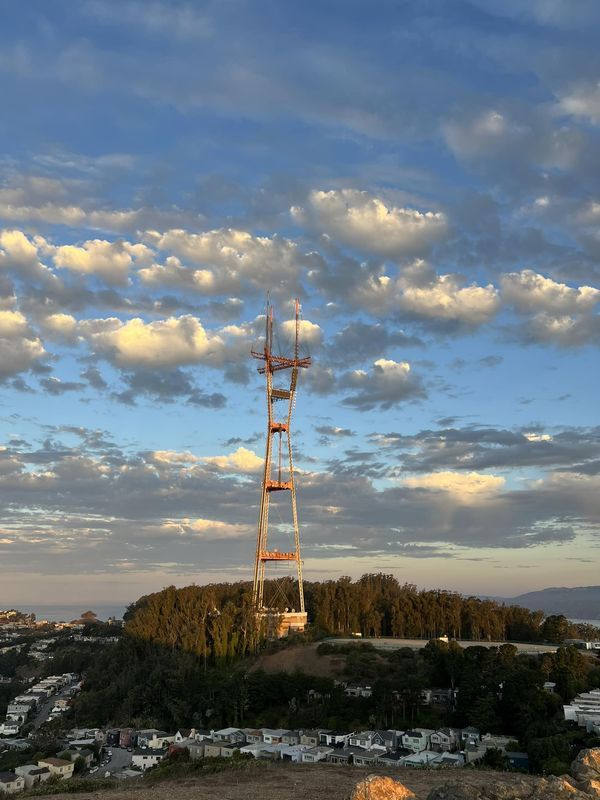 a tall tower sitting on top of a hill under a blue sky filled with clouds