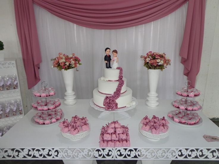 a table topped with lots of cakes and cupcakes on top of white tables