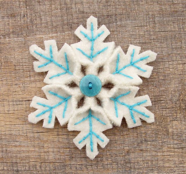 a white and blue snowflake sitting on top of a wooden table next to a button