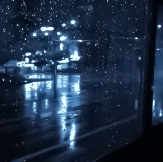 rain is falling down on the street at night