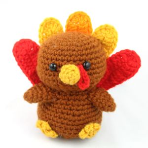 a crocheted stuffed turkey sitting on top of a white table next to a red and yellow object