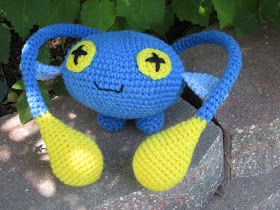 a crocheted blue and yellow stuffed animal sitting on top of a cement slab