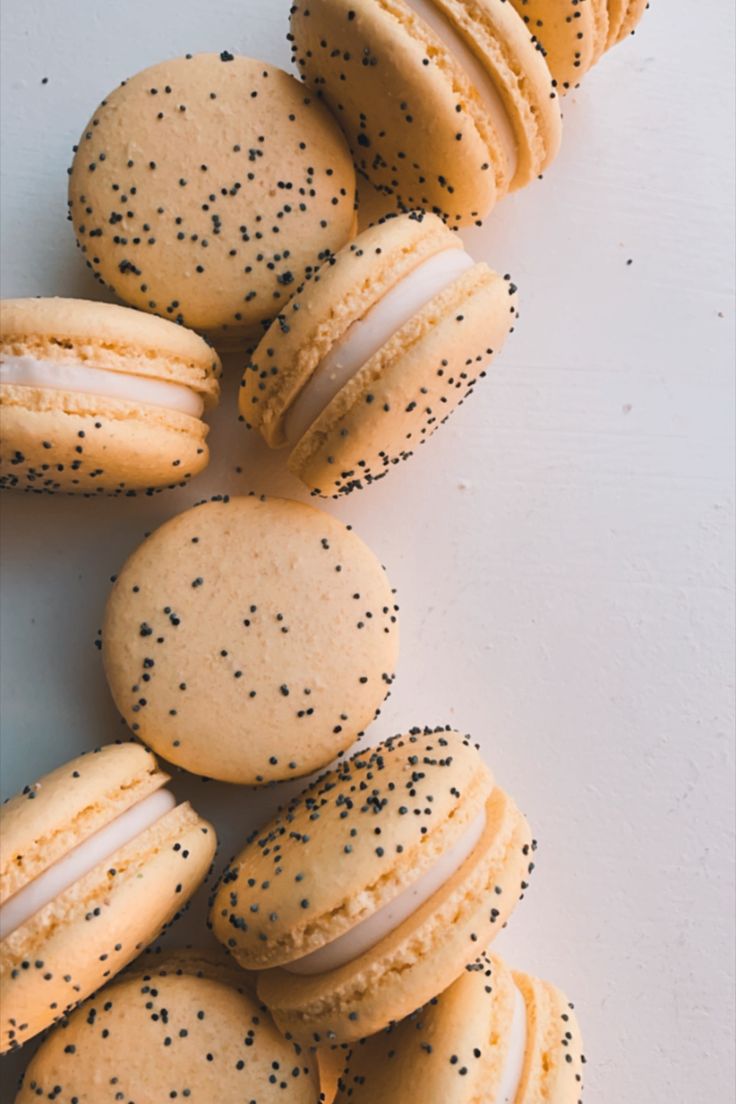 several cookies with black sprinkles are arranged on a white surface