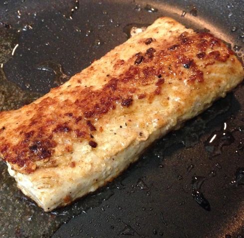 a piece of meat cooking in a frying pan with oil on the bottom,