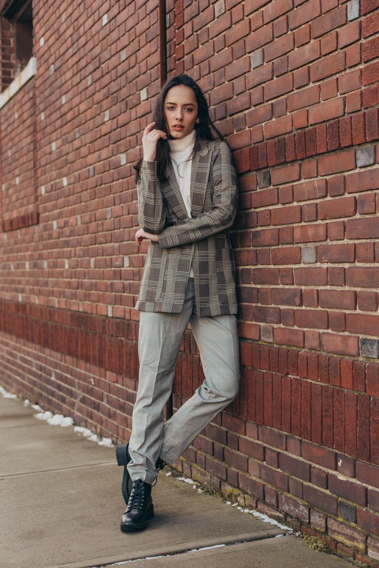 a woman leaning against a brick wall