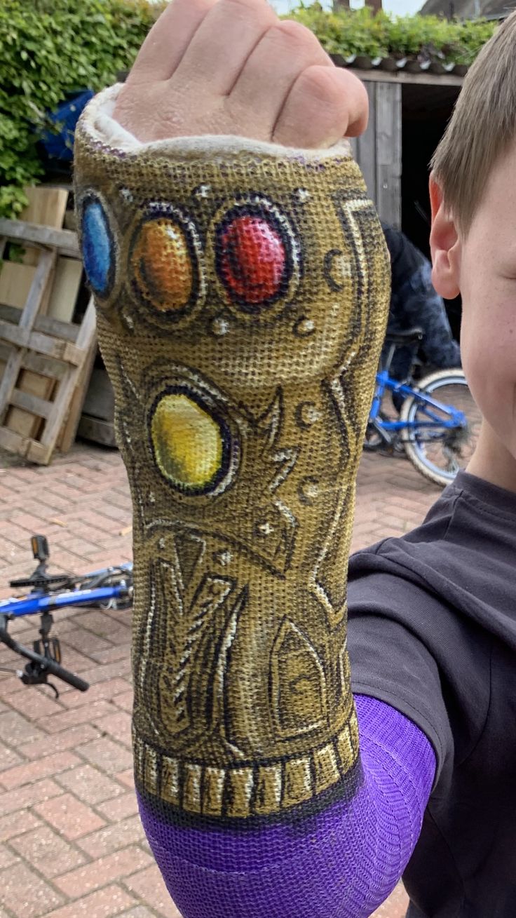 a young boy is holding up his arm covered in an intricately decorated wristband