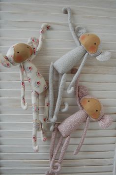 three stuffed animals hanging from the side of a window sill with blinds behind them