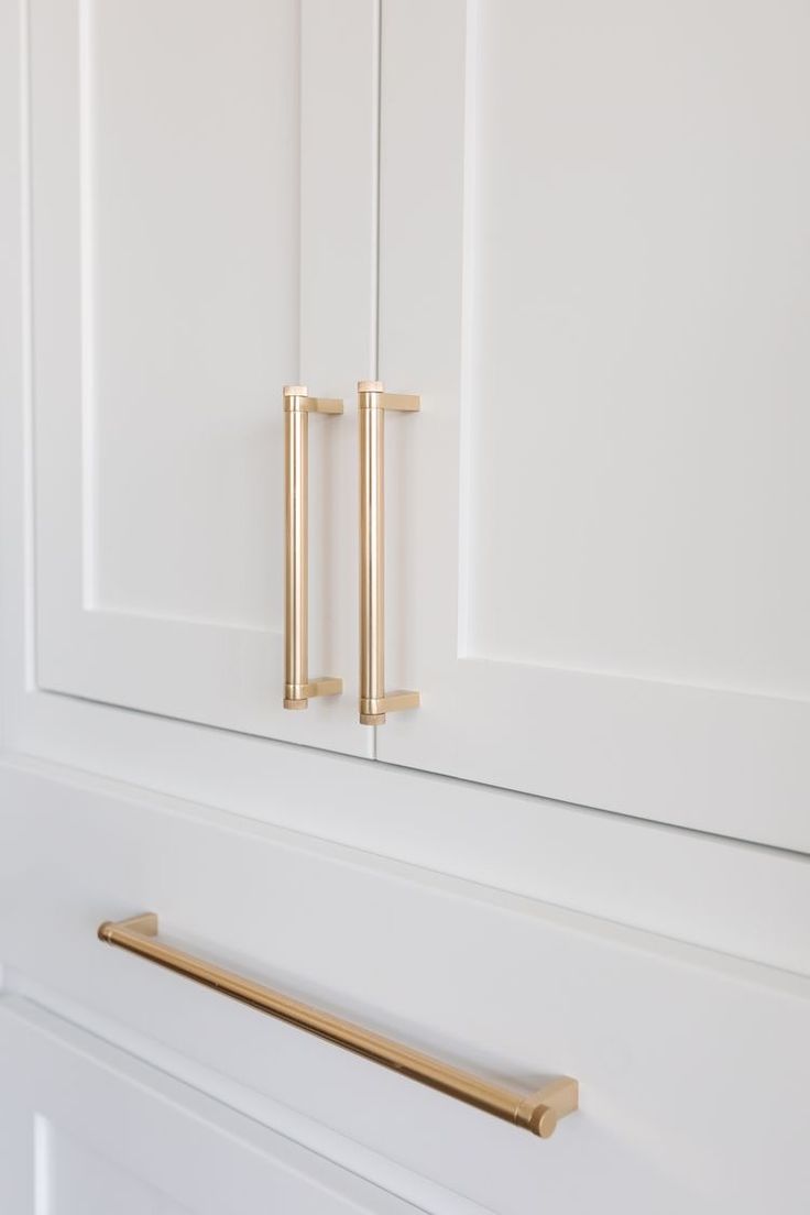 a white cabinet with brass handles and pulls