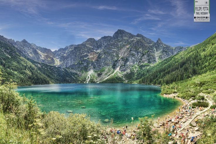 a lake surrounded by mountains with people swimming in it