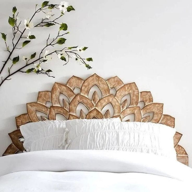 a white bed topped with a wooden headboard next to a vase filled with flowers