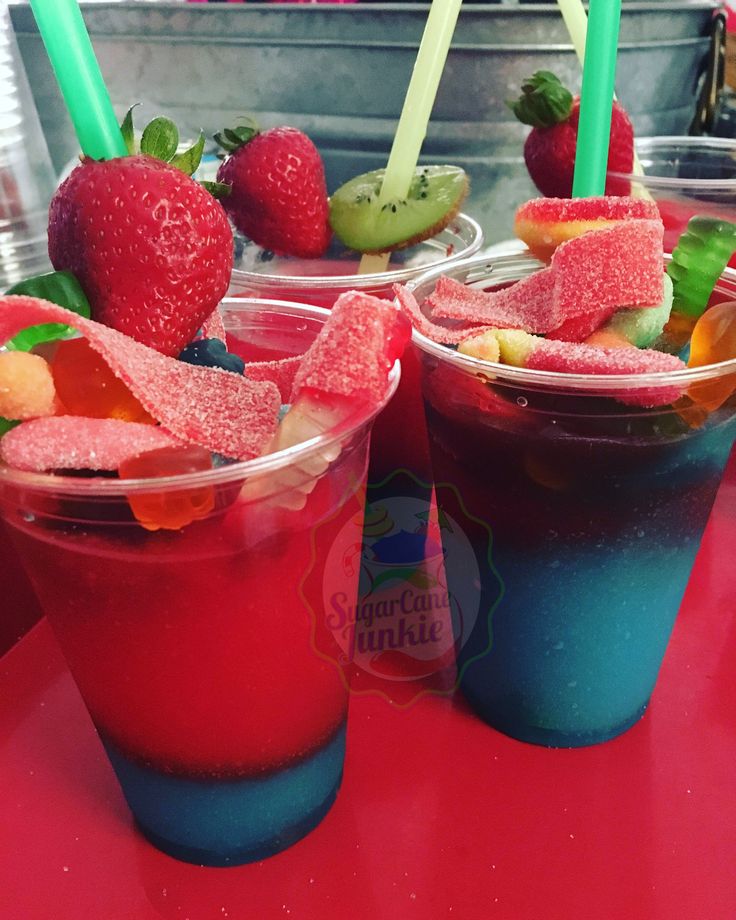 two cups filled with different types of fruit on top of a red table next to each other