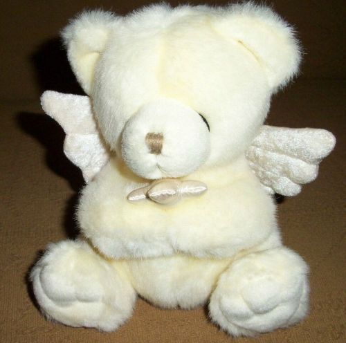 a white teddy bear with angel wings on it's chest sitting on the floor