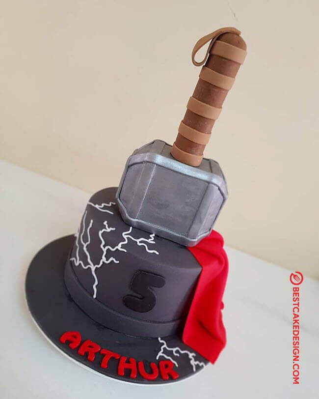 a birthday cake that looks like an thor helmet with a hammer sticking out of it