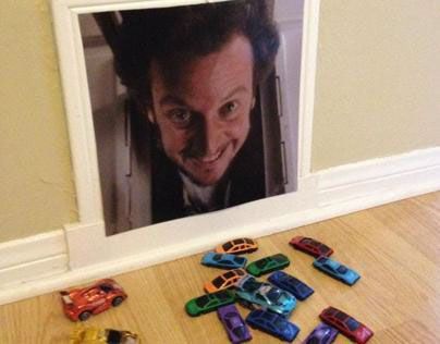 there are many toy cars laying on the floor next to a framed photo with a man's face