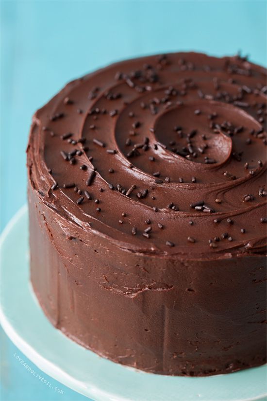 a chocolate frosted cake with sprinkles on a blue tablecloth, ready to be eaten