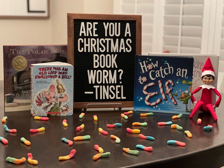 an elf is sitting on a table with some books and candy in front of him