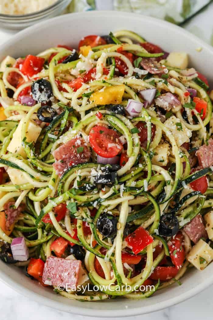 a white bowl filled with pasta and veggies on top of a marble table