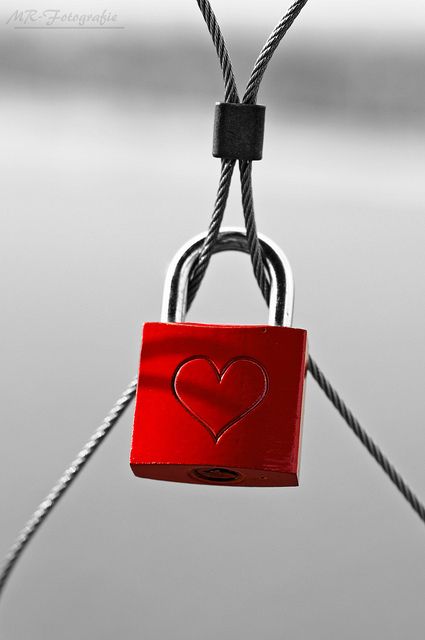 a red padlock attached to a rope with a heart on it's side