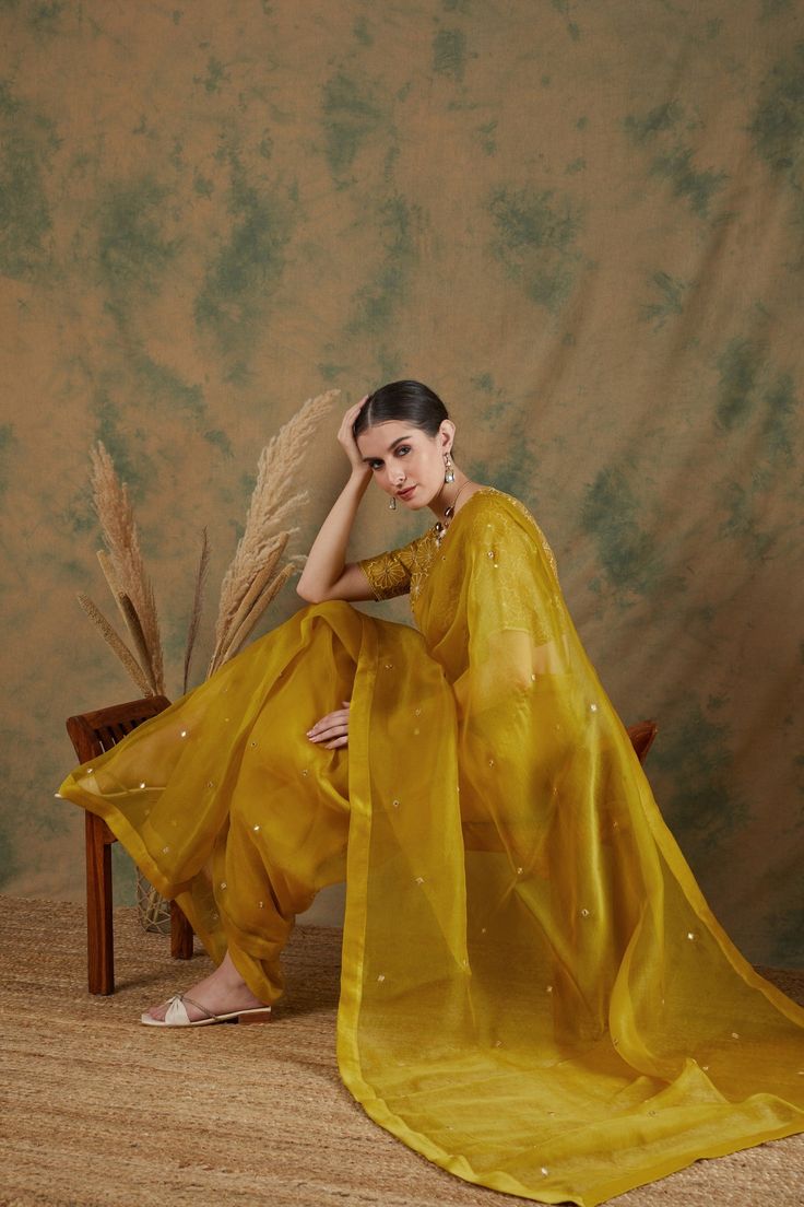 A golden yellow saree made of luxurious silk organza fabric has mirror work embroidery all over.
It is paired with a monotone embroidered blouse with monotone threadwork.
This saree is a timeless choice that you will treasure forever. Gold Pre-draped Cotton Silk Saree With Gota Work, Gold Cotton Silk Pre-draped Saree With Gota Work, Eid Pre-draped Saree In Slub Silk With Gota Work, Eid Pre-draped Saree With Gota Work In Slub Silk, Eid Pre-draped Saree With Gota Work, Gold Organza Pre-draped Saree For Navratri, Yellow Slub Silk Traditional Wear With Gota Work, Cotton Silk Saree With Mirror Work For Eid, Eid Cotton Silk Saree With Mirror Work