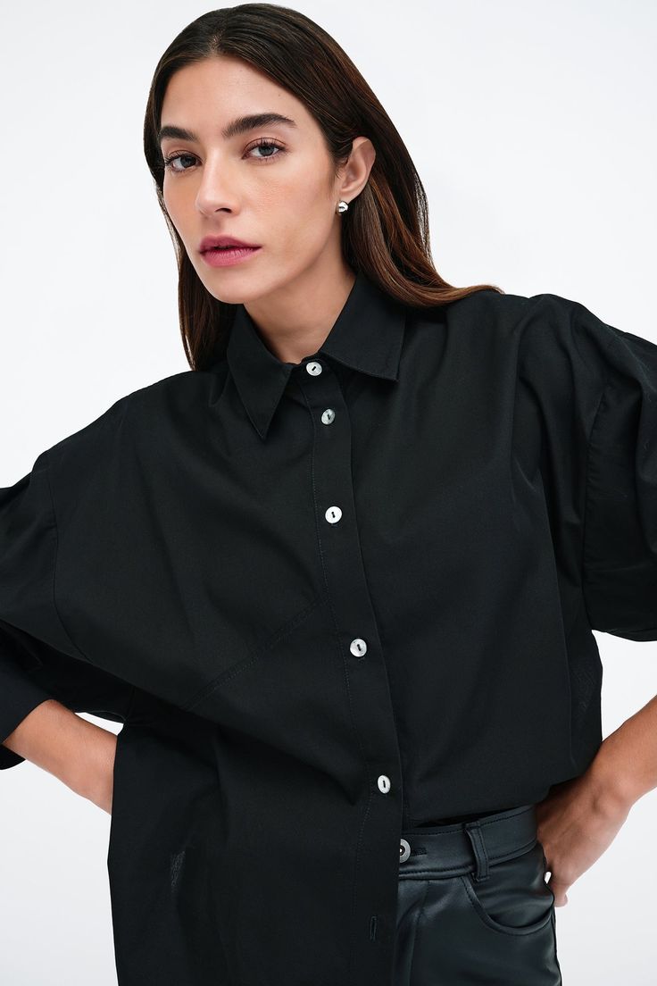 Our Ezra Shirt is a capsule wardrobe dream for your closet. Crafted from 100% crisp European poplin cotton, she offers a classic button-up silhouette in front, but with a cropped back for modern edge. Say hello, as well, to her diagonal seams at the front, sleek collar and long dolman sleeves finished with mother-of-pearl button cuffs. Wear Ezra tucked, tied or open and free—she never fails to inspire new looks.[SPLIT] Rocio, in black and in light blue, is 5'9.5" (175 cm) tall, wearing size XS. Chic Button-up Cropped Workwear Shirt, Chic Button-up Cropped Shirt For Work, Chic Poplin Shirt For Work, Chic Poplin Tops For Workwear, Chic Cropped Cotton Shirt, Chic Collared Poplin Top, Chic Button-up Poplin Blouse, Chic Relaxed Fit Button-up Cropped Shirt, Chic Relaxed Fit Cropped Button-up Shirt