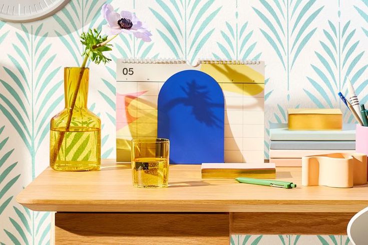 a wooden table topped with yellow vases filled with flowers next to a wall paper