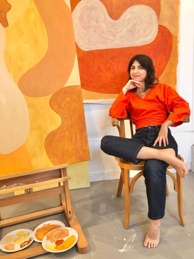 a woman sitting in a chair next to a painting