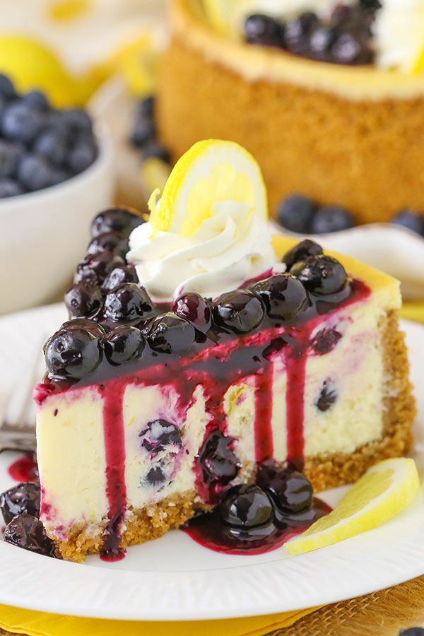 a slice of cheesecake with blueberries and lemons on the top is sitting on a plate