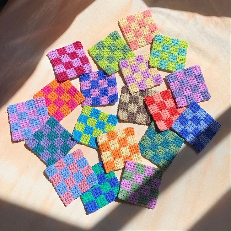 a bunch of colorful squares sitting on top of a white cloth covered table next to a window