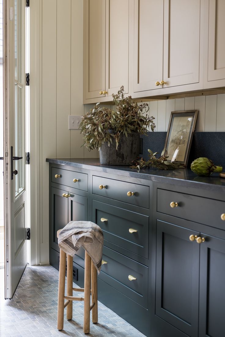 a kitchen with blue cabinets and stools next to a potted plant on the counter