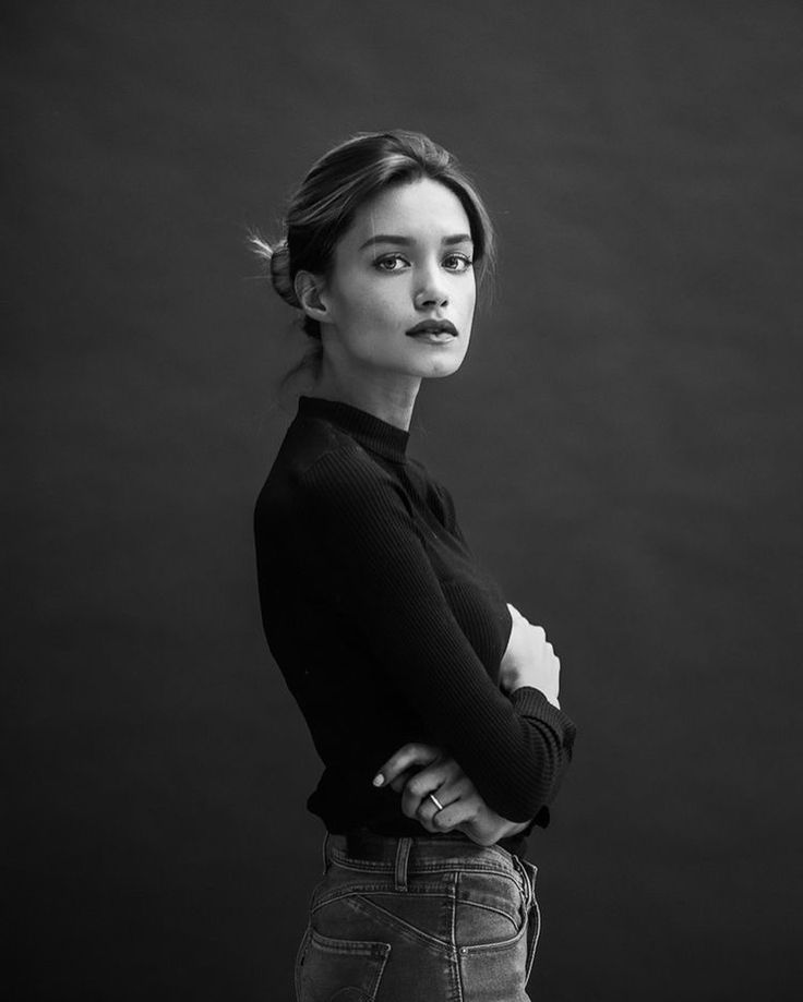 a black and white photo of a woman with her arms crossed looking at the camera