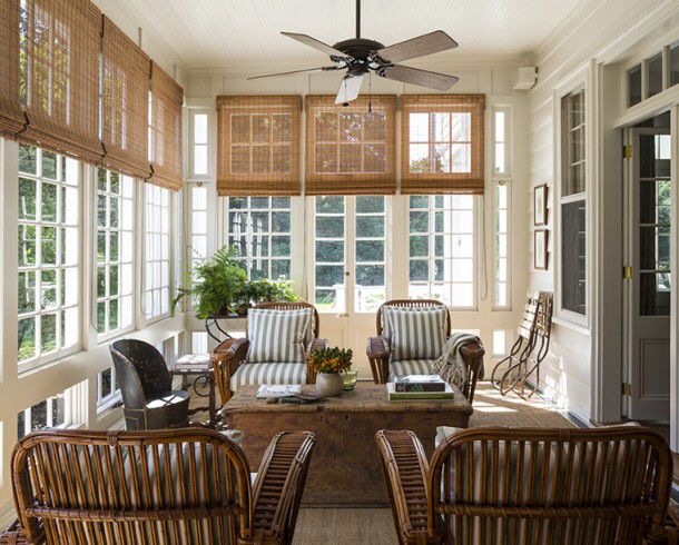 two wicker chairs sitting in front of a window with shutters on each side