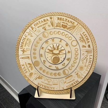 a gold plate sitting on top of a wooden table next to a black box and white wall