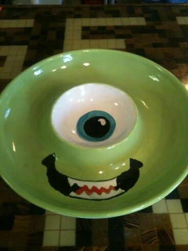 a green bowl with an evil face painted on it's side and eyes in the center