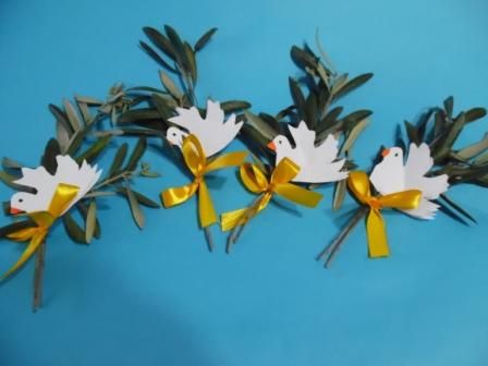 three white doves with yellow ribbons and bows on blue background, one is made out of paper