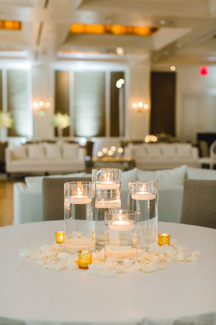 candles are placed on the table in front of white tables with chairs and couches