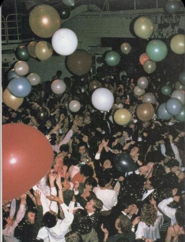 a large group of people with balloons floating in the air at a party or celebration