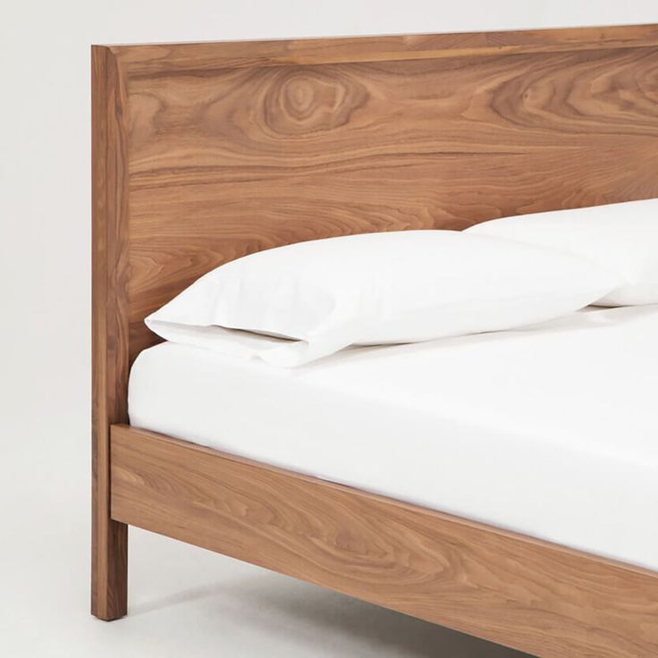 a wooden bed frame with white sheets and pillows on it's headboard, against a white background