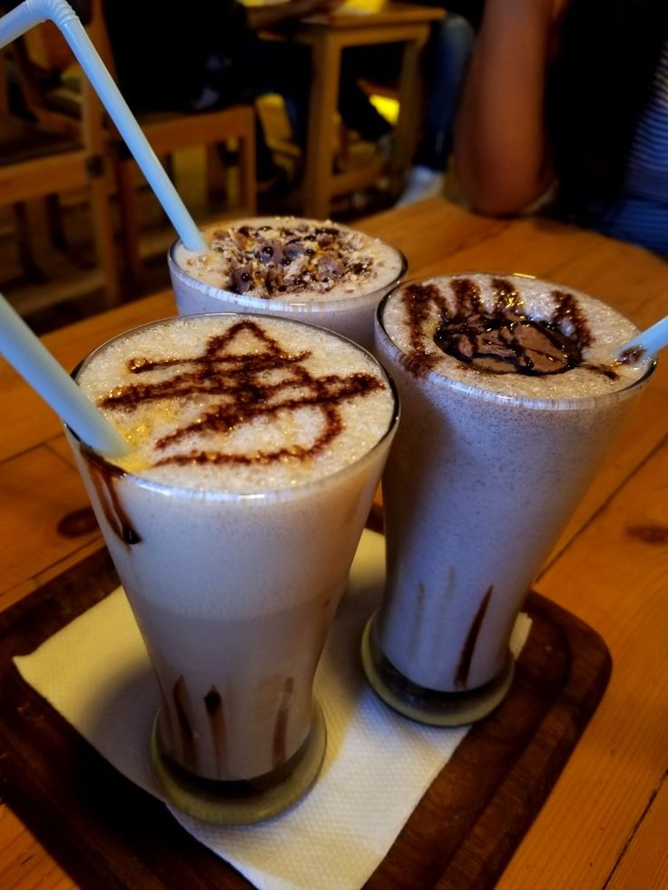 three drinks are sitting on a table with straws