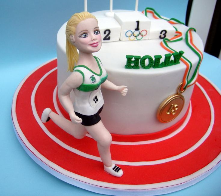 a birthday cake with a female figure on top and the number one in front of it