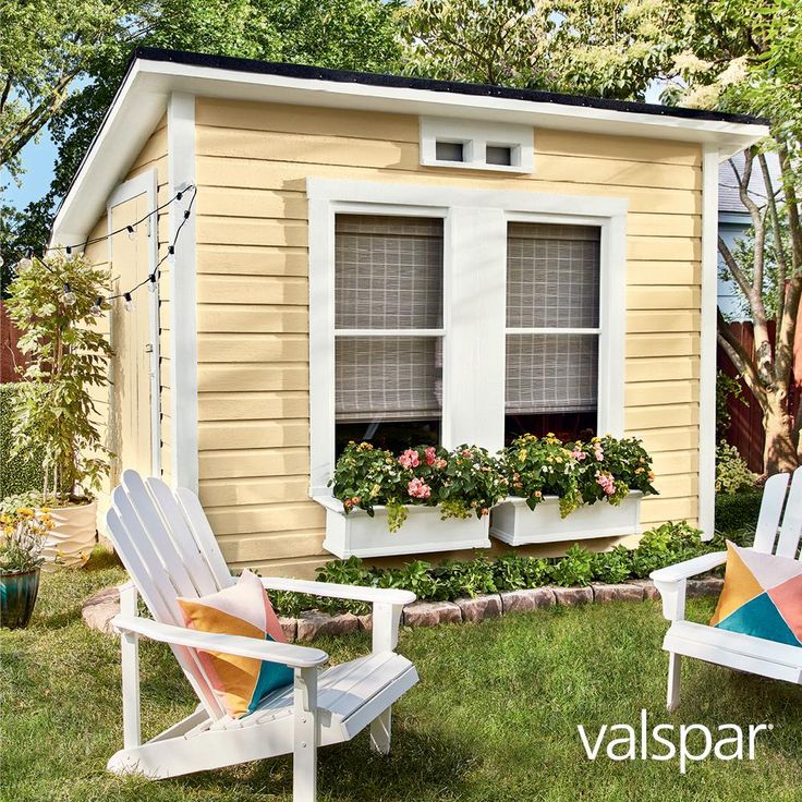 two lawn chairs sitting in front of a tiny house