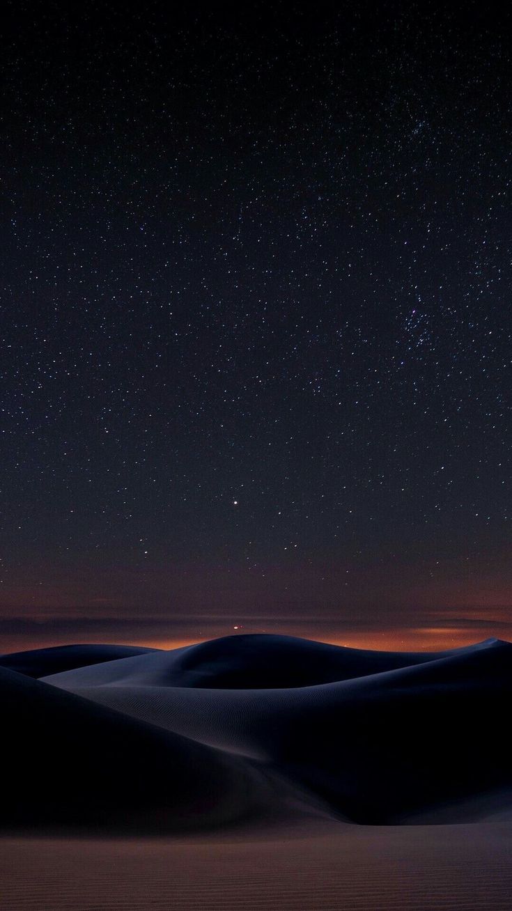 the night sky with stars above sand dunes