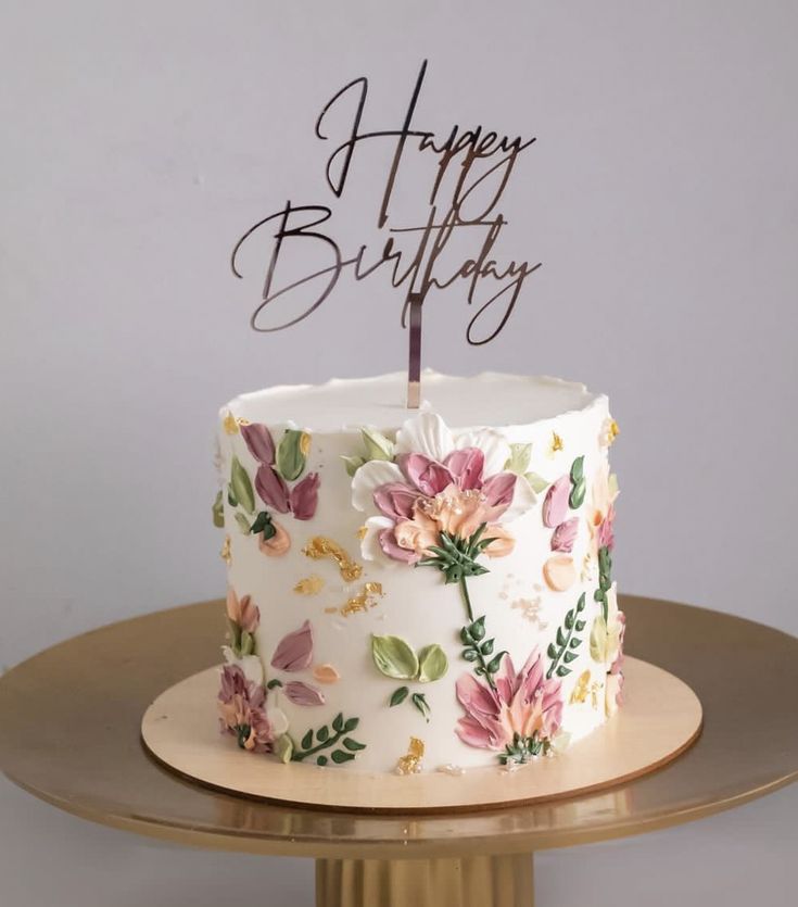 a birthday cake decorated with flowers and the words happy birthday written on top is sitting on a table