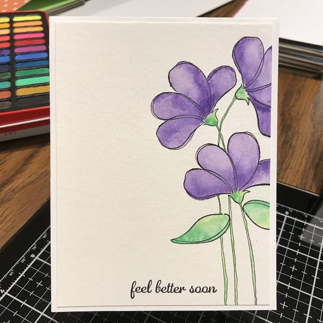 a card with purple flowers on it sitting next to colored crayon pencils