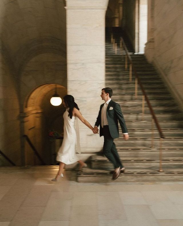 a man and woman holding hands while walking down stairs